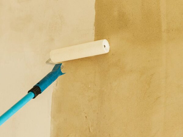 Worker priming interior walls with a roller